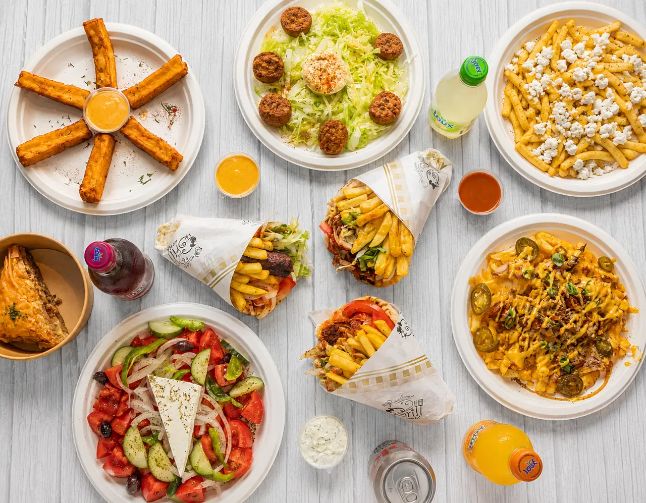 Table laid with gyros wraps, loaded fries, salad and dips
