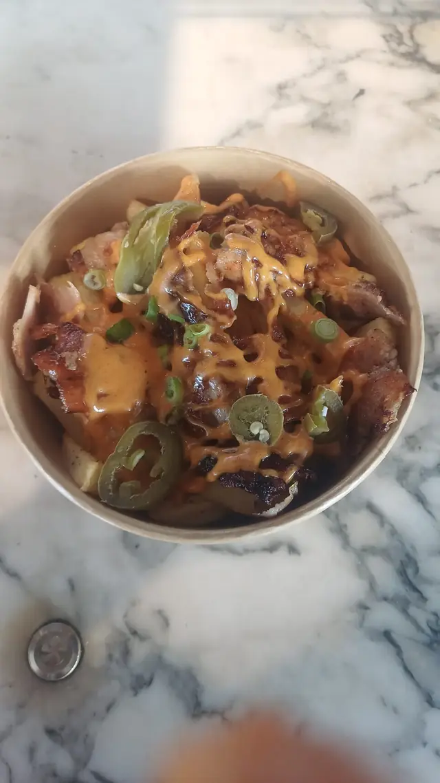 Bowl of loaded fries with cheese, spring onions and jalapeños